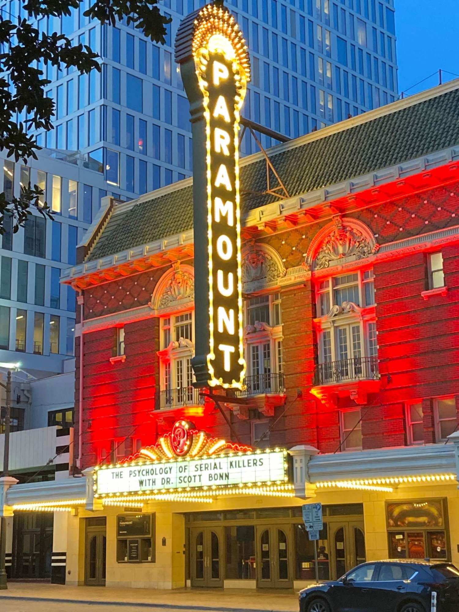 Illuminated Paramount theater with marquee about psychology event at dusk.